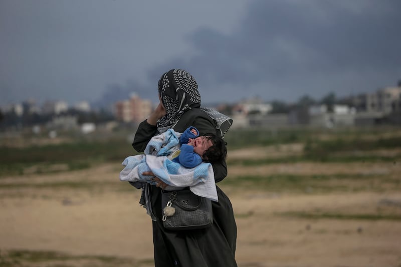 A Palestinian mother carries her baby along Gaza's Al Rashid road. About 9,000 women have been killed by Israel forces in the war so far, with an estimated 37 mothers dying every day, according the the UN. EPA