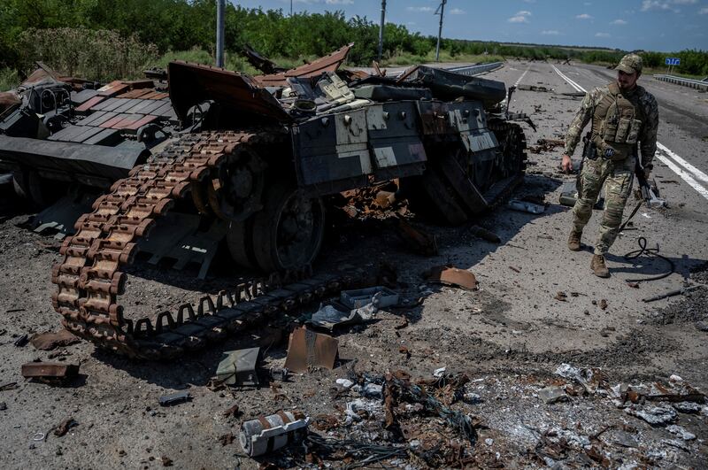 A Ukrainian serviceman walks near a destroyed Ukrainian tank, as Russia's attack on Ukraine continues
