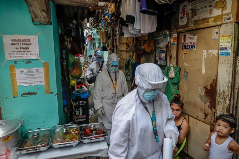 Health workers walk past a food vendor inside an alley while doing rounds in Manila, Philippines. Four volunteer health workers were nicknamed 'Astronauts' by residents of Village 775, Zone 84 in Manila as they resemble such when donning their protective equipment. The healthcare volunteers conduct home visits twice a day to people infected or suspected to be infected with the novel SARS-CoV-2 coronavirus that causes the COVID-19 disease in one of the densely populated villages in Manila.  EPA