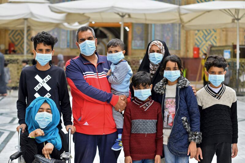 Members of an Iraqi family, all wearing masks, pose for a picture during their visit to the shrine of Imam Ali in the holy Iraqi central city of Najaf.  AFP