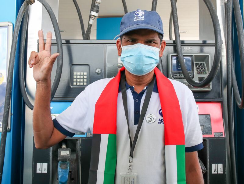 A staff at Adnoc petrol station proudly wears a UAE scarf to celebrate UAE flag day in Khalifa City, Abu Dhabi. Victor Besa / The National