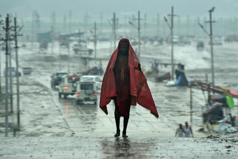 A man wraps a plastic sheet to cover himself as heavy rain continues in Allahabad on Wednesday. AFP