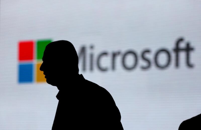 FILE - In this Tuesday, Nov. 7, 2017, file photo, an unidentified man is silhouetted as he walks in front of Microsoft logo at an event in New Delhi, India. Microsoft Corp. reports earnings Wednesday, Jan. 31, 2018. (AP Photo/Altaf Qadri)