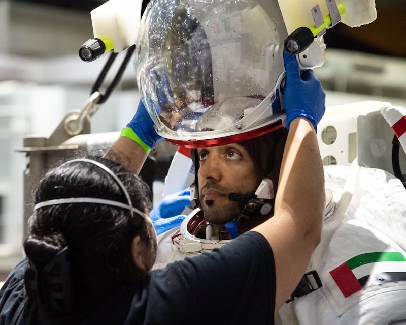 Sultan Al Neyadi puts his helmet on for spacewalk training under water. Mr Al Neyadi was one of two people selected from 4,022 candidates to become the first Emirati astronauts. Mbrsc