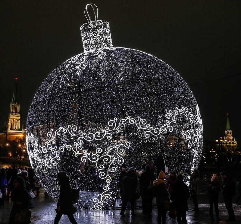 Russian people passes a huge light Christmas toy in front of Moscow Kremlin, Russia on December 19, 2014. 244 Christmas tree markets open in the capital. Sergei Ilnitsky / EPA