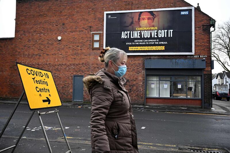 A pedestrian walks past a coronavirus information poster near a temporary testing facility at the Walsall Arena & Arts Centre in Walsall. AFP