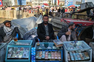 Money changers wait for customers along a street in Kabul. AFP