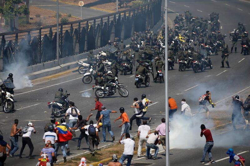 Opponents to Mr. Maduro confront loyalist Bolivarian National Guard troops firing tear gas at them. AP Photo