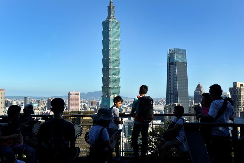 People gather on a viewing deck at Elephant Mountain before Taipei 101 Tower (C) and Nan Shan Tower (centre R) in Taipei on July 14, 2018. (Photo by Chris STOWERS / AFP)