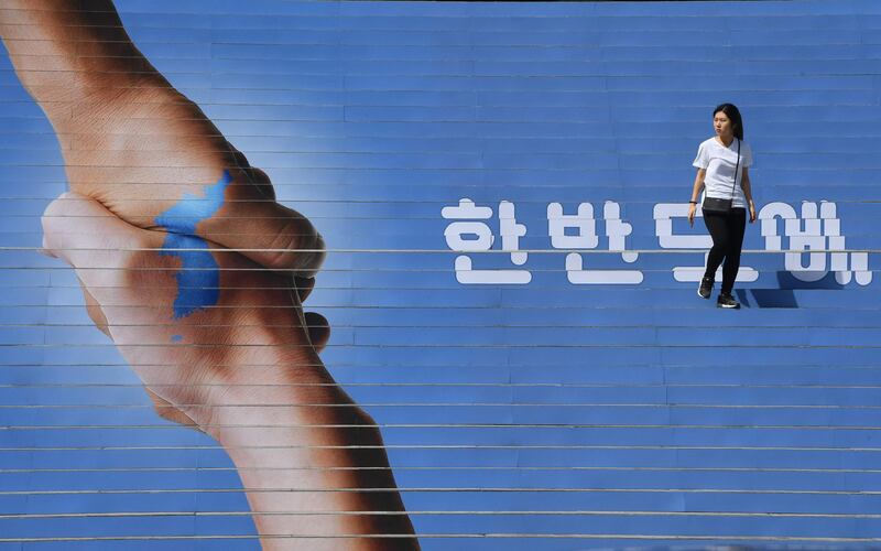 A woman walks on the stairs decorated with an image of two hands shaking to form the shape of the Korean Peninsula to support the upcoming inter-Korean summit, in downtown Seoul. Jung Yeon-je/AFP