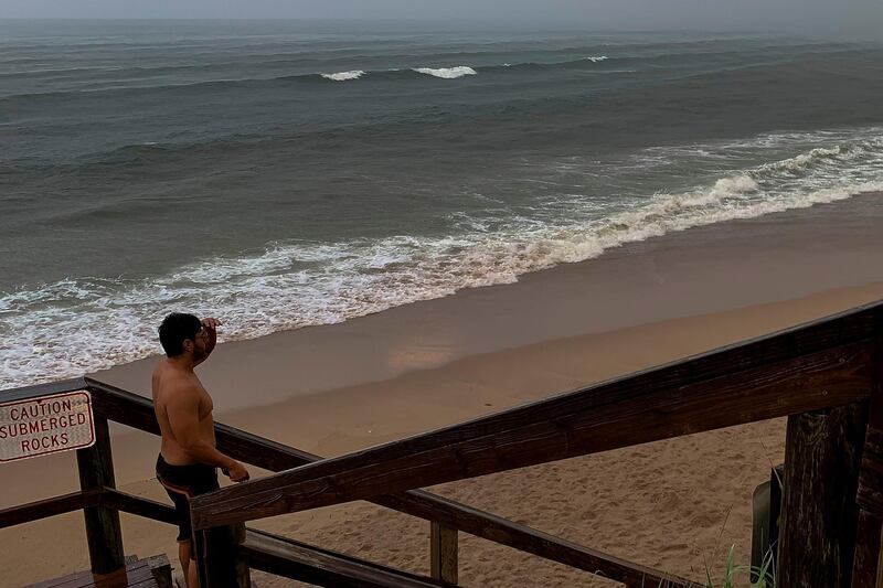 A man looks at the ocean in pouring rain. AFP