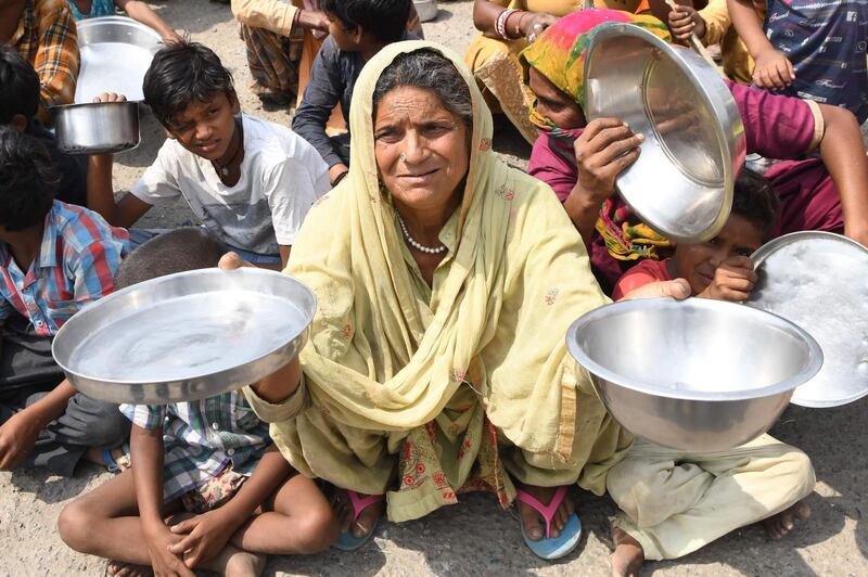 Families from Maharashtra hold out utensils to protest the lack of food in a slum area on the outskirts of Amritsar, Punjab, May 31. Narinder Nanu / AFP