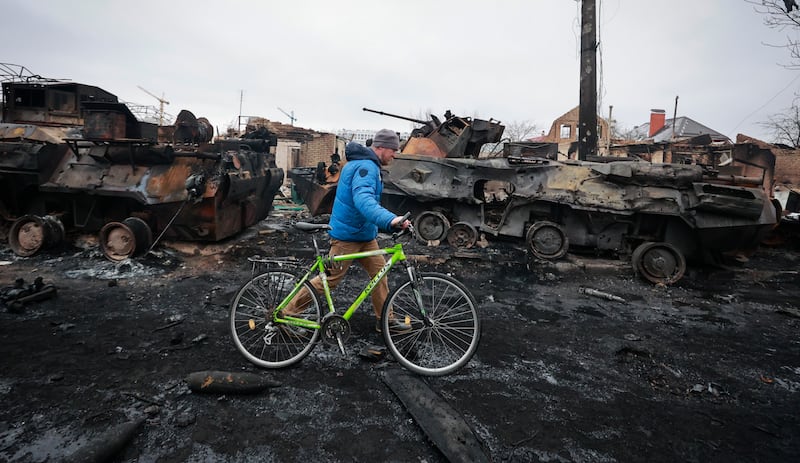 A man walks past the remains of Russian military vehicles in Bucha, close to Kyiv. AFP