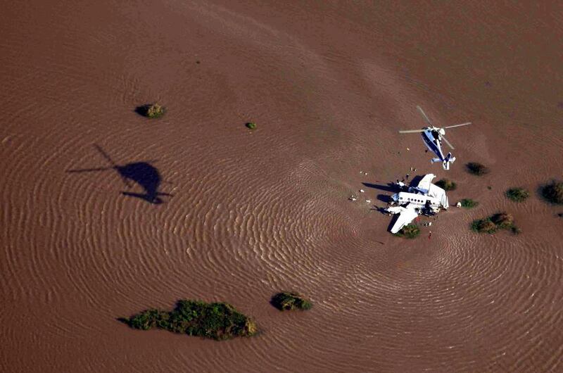 A handout picture provided by the Uruguayan Air Force shows a helicopter flying over an Argentinian aircraft which crashed into the River Plate, close to Colonia, Uruguay. The Argentinian Government confirmed that five people died and four were injured after the crash. Uruguayan Air Force/ EPA