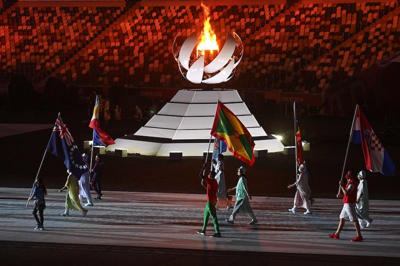 Athletes carrying nations' flags walk past the Olympic flame as they enter the stadium during the closing ceremony.