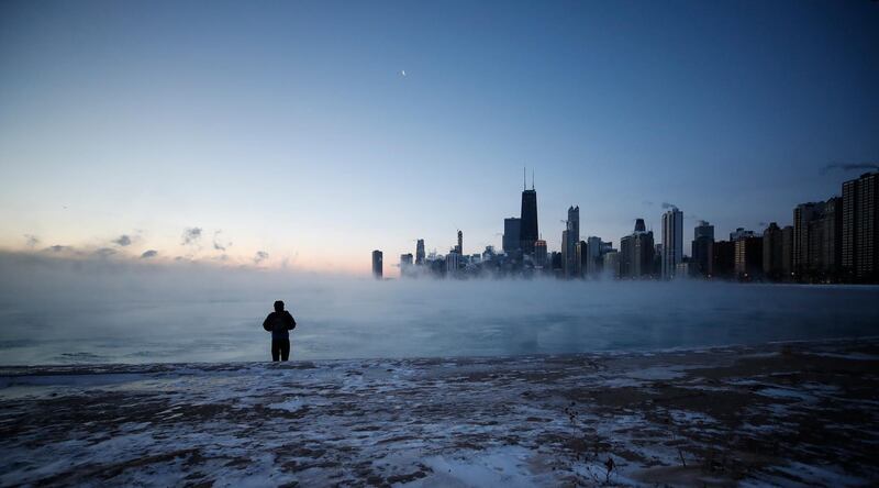 A man walks on North Avenue Beach as the sun rises over Lake Michigan in Chicago. EPA