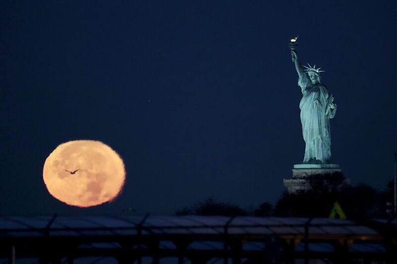 The supermoon appears near the Statue of Liberty in New York City. Julio Cortez / AP Photo