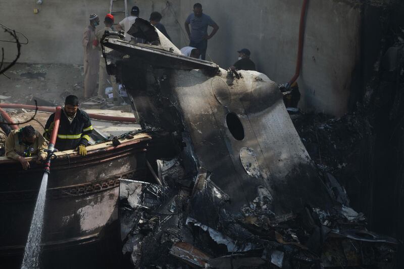 A firefighter sprays water on the wreckage of a Pakistan International Airlines aircraft after it crashed in a residential area in Karachi. AFP