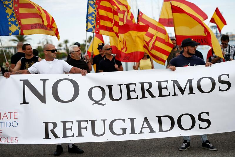 People hold a banner reading 'We don't want refugees' during a demonstration called by the far-right political party Espana 2000 (E-2000) against the arrival of the Aquarius rescue ship in Valencia on June 16, 2018. The boat, which is due to arrive in Spain on Sunday morning with more than 600 people on board, has been the heart of a major migration row between European Union member states. / AFP / PAU BARRENA
