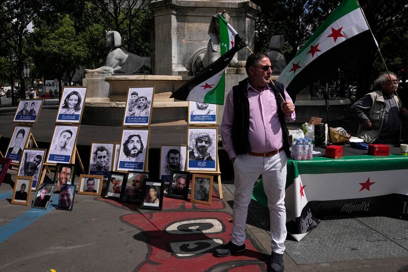 Activists hold Syrian flags next to portraits of alleged victims of the Syrian regime outside the court in Paris where the trial was held. AP