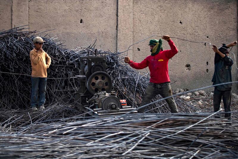 Workers straighten iron rods.