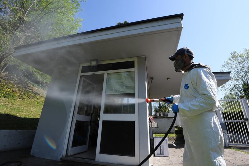 A worker wearing protective clothing sprays disinfectant towards a building in Via Cortina d’Ampezzo in Rome, as the spread of the coronavirus disease continues. Reuters