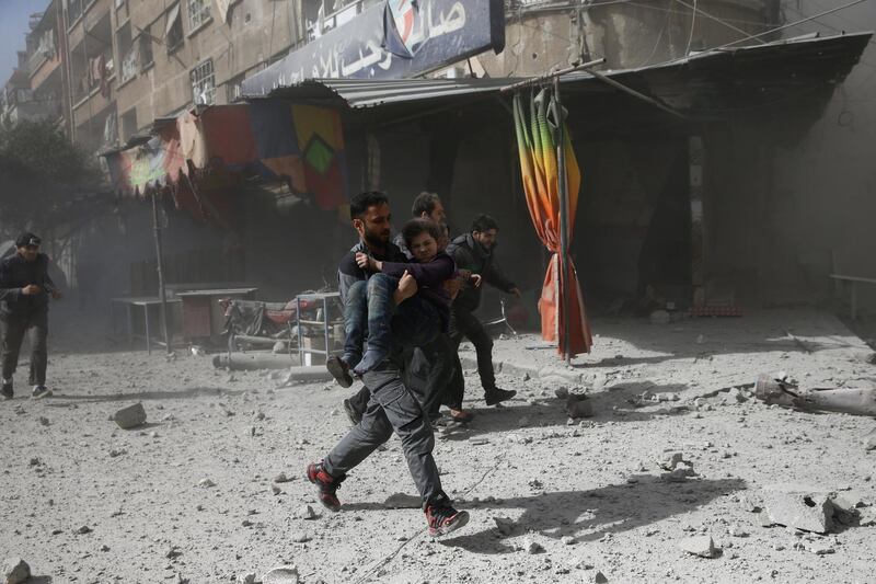A man runs as he holds a girl after an air strike on Douma on February 7, 2018. Bassam Khabieh / Reuters