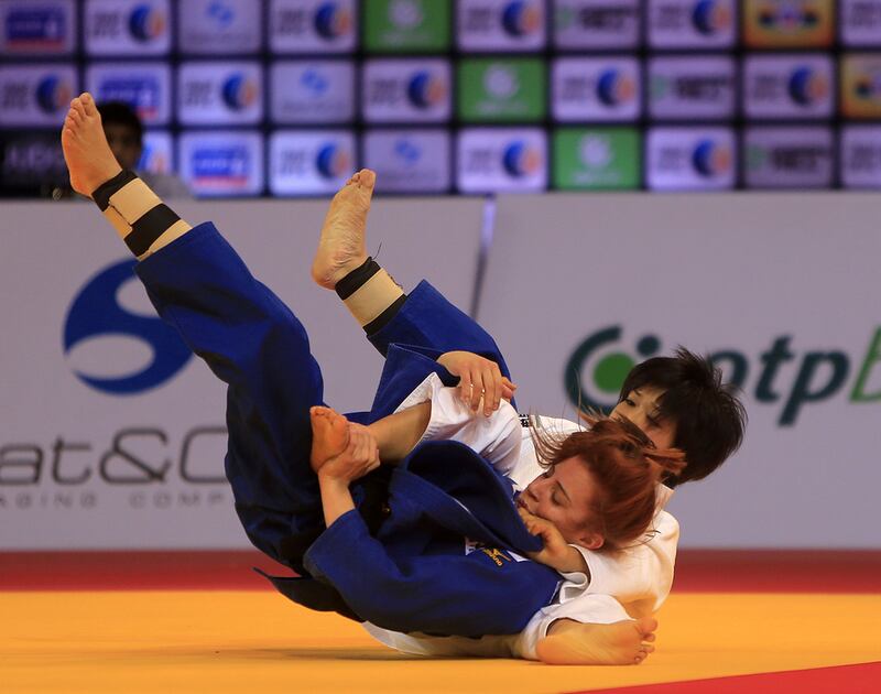 Nathalia Mercadante, in blue from Brazil, fights with Funa Tonaki from Japan on the opening day of the International Judo Federation (IJF) Junior World Championships, which started at the Ipic Arena at the Zayed Sports City in Abu Dhabi on Friday. Ravindranath K / The National