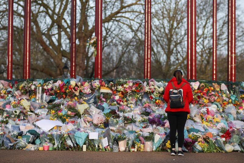 A woman looks at flowers at a memorial site at the Clapham Common Bandstand, following the kidnapping and murder of Sarah Everard, in London, Britain, March 17, 2021. REUTERS/Hannah McKay