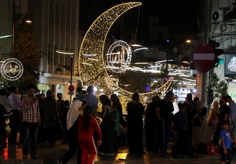 Jordanian shoppers walk past a giant Crescent Moon.  EPA