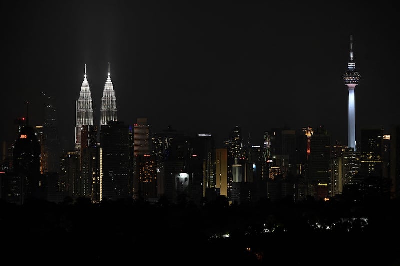 Malaysia's landmark Petronas Twin Towers (L) and KL Tower (R) are illuminated before their lights are turned off to mark the Earth Hour environmental campaign in Kuala Lumpur. AFP