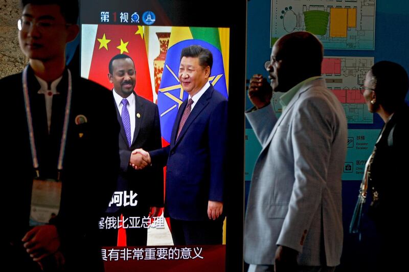 African delegates walk by a screen panel showing a footage of Chinese President Xi Jinping with Ethiopia's Prime Minister Abiy Ahmed ahead of the Forum on China-Africa Cooperation in Beijing, Monday, Sept. 3, 2018. African leaders will likely press their Chinese hosts at a conference this week to help narrow their trade deficits with Beijing by shifting more manufacturing to their continent, the chief executive of the biggest African bank said. (AP Photo/Andy Wong)