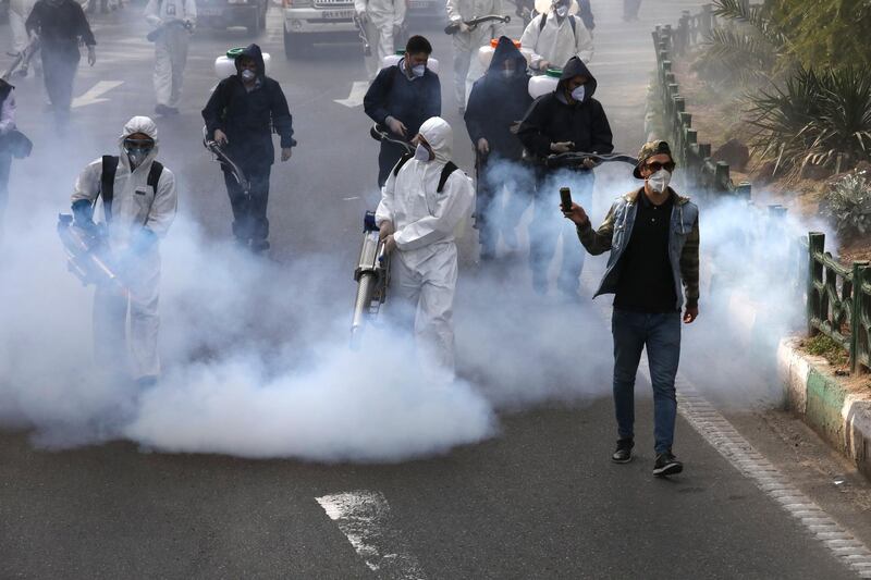 Firefighters disinfect a square against the new coronavirus as a man takes film, in western Tehran, Iran. AP Photo