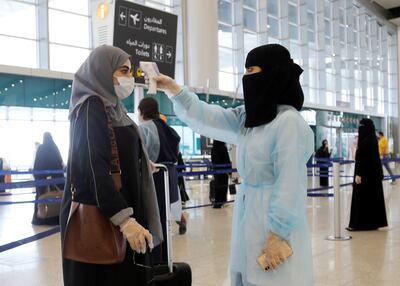 A security woman checks the temperature of a woman at Riyadh International Airport, after Saudi Arabia reopened domestic flights, following the outbreak of the coronavirus disease (COVID-19), in Riyadh, Saudi Arabia May 31, 2020. REUTERS/Ahmed Yosri