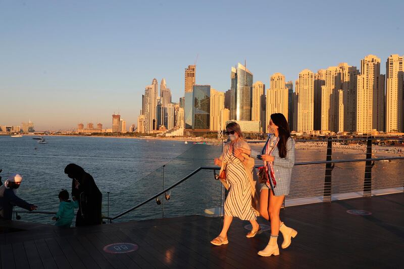 Tourists walk along the bridge from Jumeirah Beach Residence to Bluewaters Island on a cool January day. The city is one of the global hubs fully open to tourists, who have flocked there for a break from lockdown at home. AP