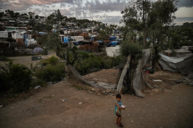 A child walks in a improvised tents camp near the refugee camp of Moria in the island of Lesbos on June 21, 2020. - Greece's announcement that it was extending the coronavirus lockdown at its migrant camps until July 5, cancelling plans to lift the measures on June 22, coincided with World Refugee Day on June 27, 2020. (Photo by ARIS MESSINIS / AFP)