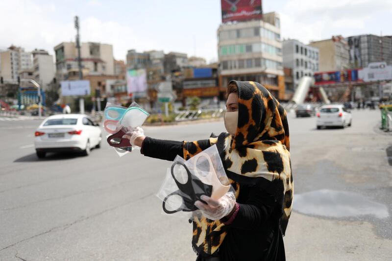 A woman wears a protective face mask and gloves, amid fear of the coronavirus disease (COVID-19), as she sells the masks in Tajrish square in Tehran, Iran. REUTERS