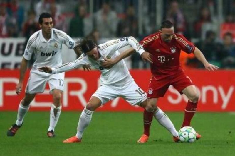 Real Madrid's Mesut Oezil, centre,challenges Bayern Munich's Franck Ribery in the first-leg of their Uefa Champions League semi-final.