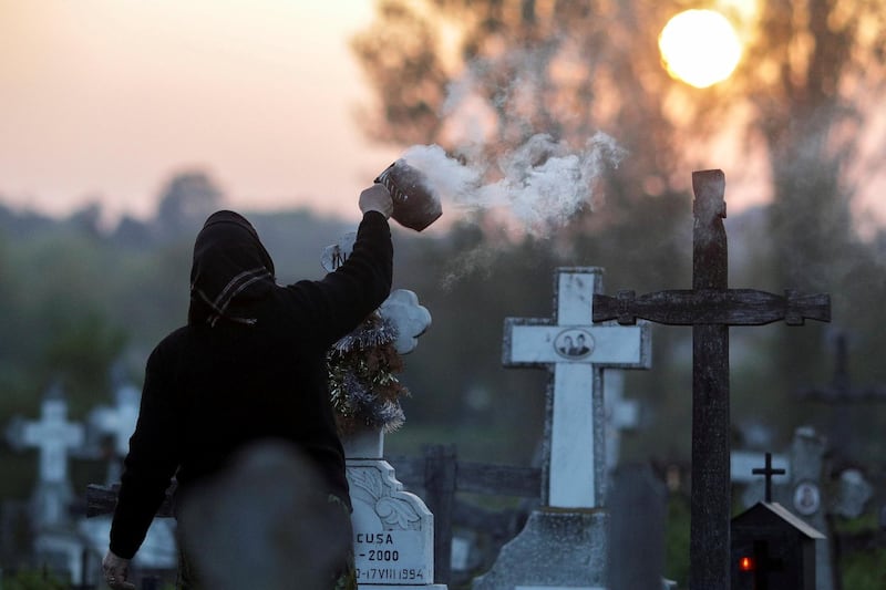 A woman burns incense near the grave of a relative in a cemetery 50 kilometers south west of Romanian capital Bucharest. Reuters