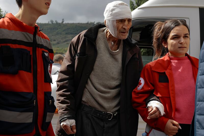 A wounded Armenian man from Stepanakert, Nagorno-Karabakh, is helped by volunteers as he arrives in Goris, Armenia. AP