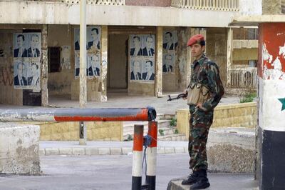 A Syrian soldier stands guard outside the Beirut headquarters of the Syrian army intelligence, 05 March 2005. Units from the Lebanese army briefly took up positions near the Syrian army intelligence offices in the afternoon and later withdrew, an AFP correspondent witnessed. Portraits on the walls show Syria's late president Hafez al-Assad and his son and successor Bashar al-Assad. EDS NOTE: Clarifying that Lebanese army troops took positions and then withdrew from the area this afternoon. AFP PHOTO/STR (Photo by - / AFP)