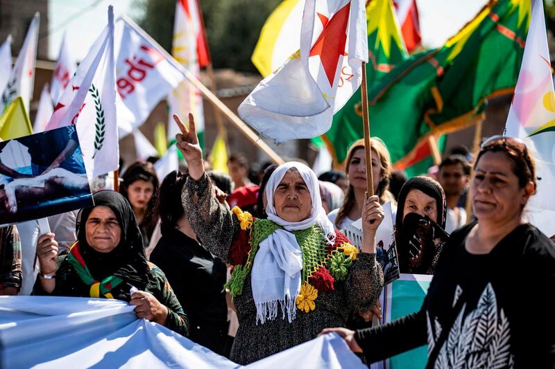 A Syrian Kurdish woman flashes the victory sign as she lifts a flag during a demonstration in the northern Kurdish-majority city of Qamishli in Hasakeh province, to express opposition to Turkey and its local allies, and rejection of their one-year-old control over the Syrian areas of Ras al-Ain, Afrin, and Tal Abyad.  AFP