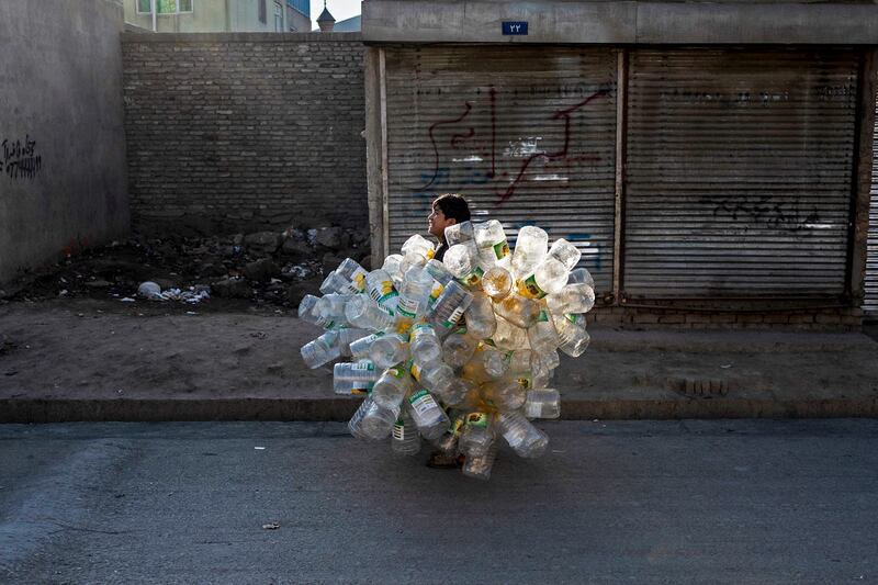 An Afghan boy carrying empty plastic containers walks along a street in Kabul. AFP