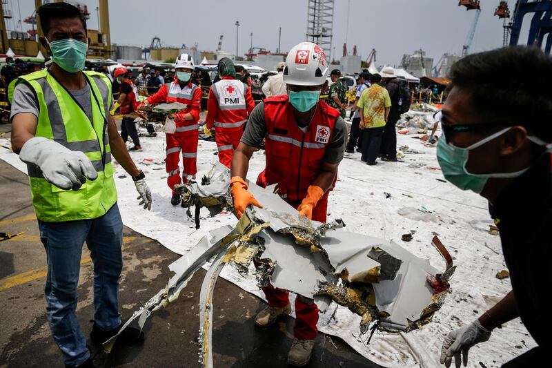 Indonesian rescuers sort through plane debris at port.