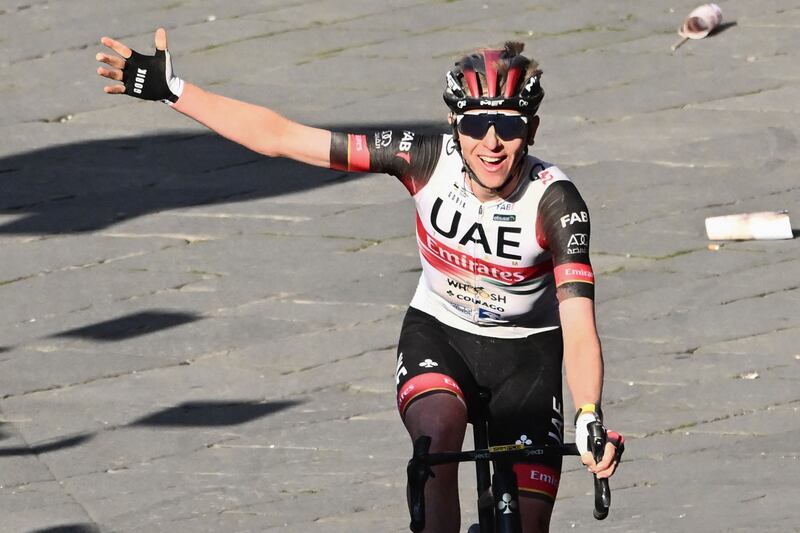 Tadej Pogacar celebrates as he crosses the finish line to win the 16th one-day classic cycling race Strade Bianche. AFP