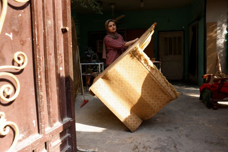 Carpenter Noor Al Janabi carries a piece of furniture.