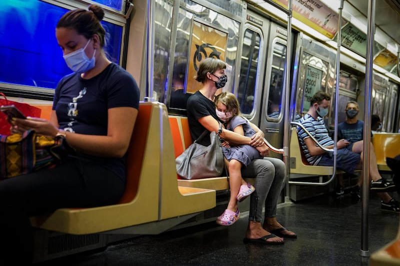 A child rests on a subway car while riders wear protective masks due to Covid-19 concerns in New York, US. AP Photo