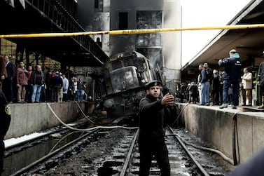 Policemen stand guard in front of a damaged train inside Ramses Station in Cairo. AP