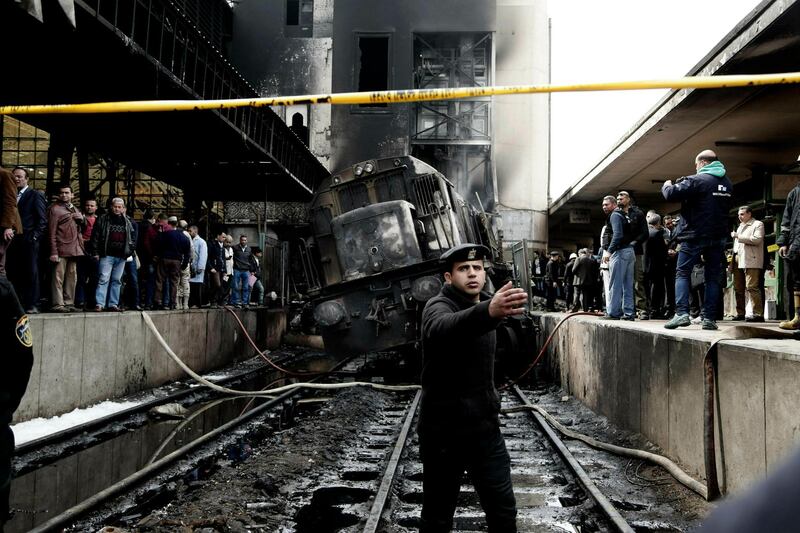 Policemen stand guard in front of a damaged train inside Ramsis train station in Cairo, Egypt, Wednesday, Feb. 27, 2019. An Egyptian medical official said at least 20 people have been killed and dozens injured after a railcar rammed into a barrier inside the station causing an explosion of the fuel tank and triggering a huge blaze that engulfed that part of the station. The head of the Cairo Railroad Hospital said the death toll is expected to rise further. (AP Photo/Nariman El-Mofty)