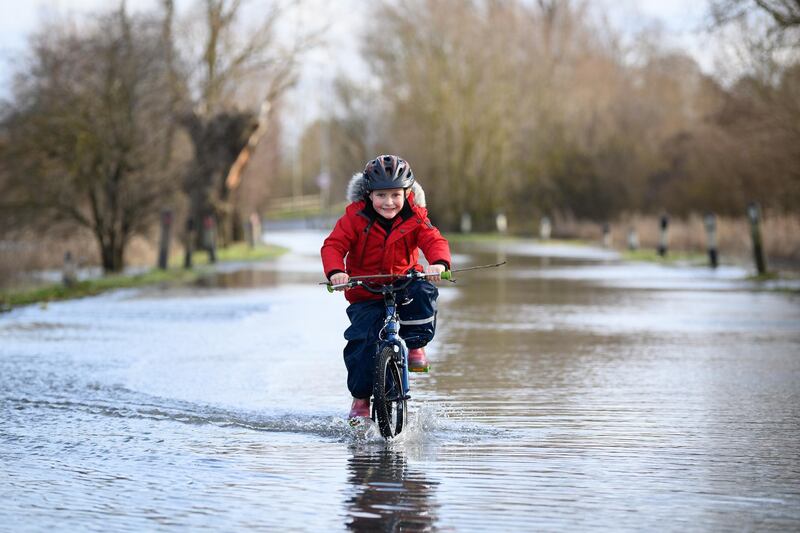 A child cycles along the flooded road by the River Great Ouse in Earith. Getty Images